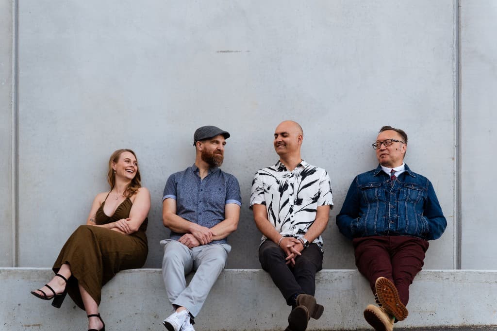 Midnight Fizz — Sammie Campbell, Kane Sherwood, Manuel Kahura, and Sam Shirley seated on a concrete ledge